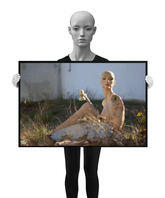 un4rt - almost human gallery poster mockup picture with a mannequin sitting outdoor next to an old satelite dish. white stonewall in the background. the poster is held by a mannequin.