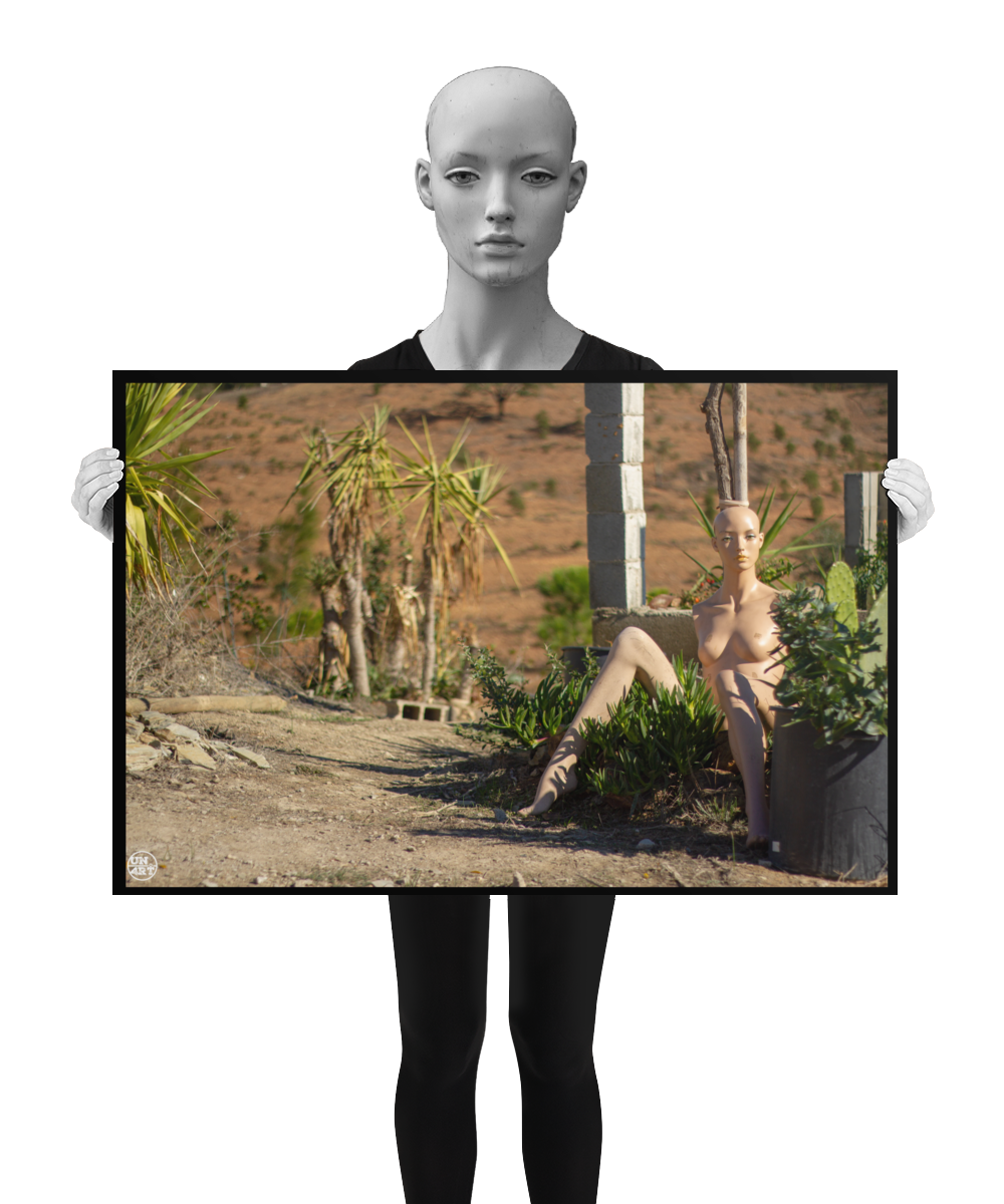 un4rt - almost human gallery poster mockup picture with a mannequin sitting outdoor in between some plants. the poster is held by a mannequin.