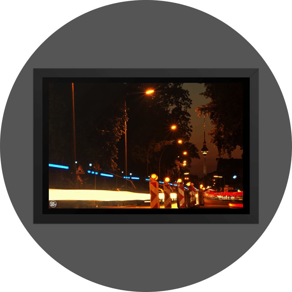 un4rt - the photographie shows a street in berlin. the street is called "puschkinallee" and the view goes along a construction site. at the end of the street berlin´s television tower is clearly visible. time lapse. golden hour. trees and city lights.