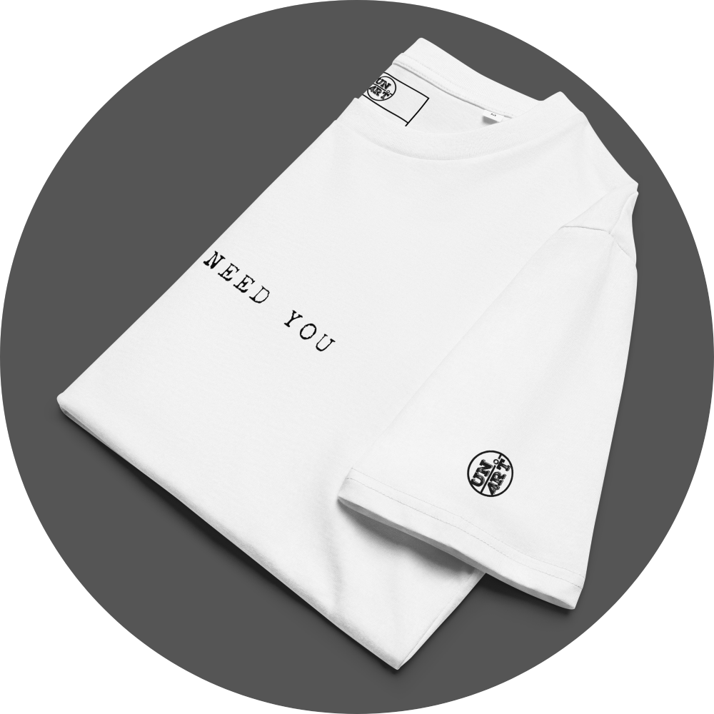 un4rt - the image shows a folded white cotton t-shirt with black letters printed on the front. only a part of the letters is visible, reading "need you". a black "UN4RT"-logo is printed on the left sleeve.