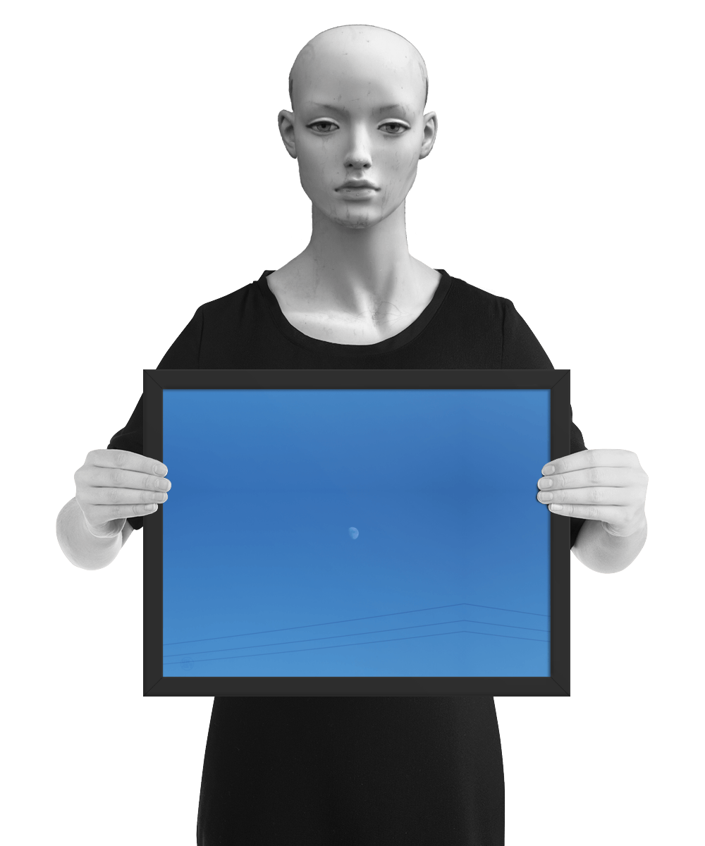 un4rt - the photographie shows a completely blue sky with a small moon in the center. some power lines cross the image on the bottom. the image is framed and presented by a mannequin in black and white.
