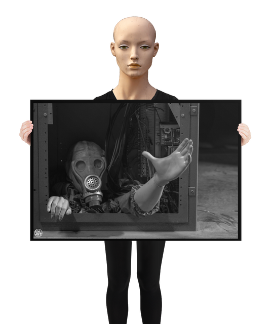 un4rt - a poster. black and white photographie of a mannequin wearing a gas mask. the mannequin stretches out one arm and reaches for help. the body is stuck inside a box with wires and electronic parts. a mannequin is holding the poster.