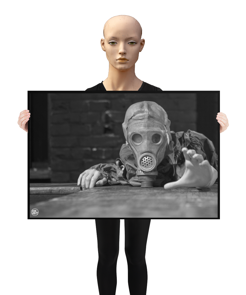 un4rt - a poster. black and white photographie of a mannequin wearing a gas mask. the mannequin stretches out one arm and reaches for help. the mannequin lies on a wooden planket, but the body is not visible. direct front view. black brick wall in the background. a mannequin s holding the poster.