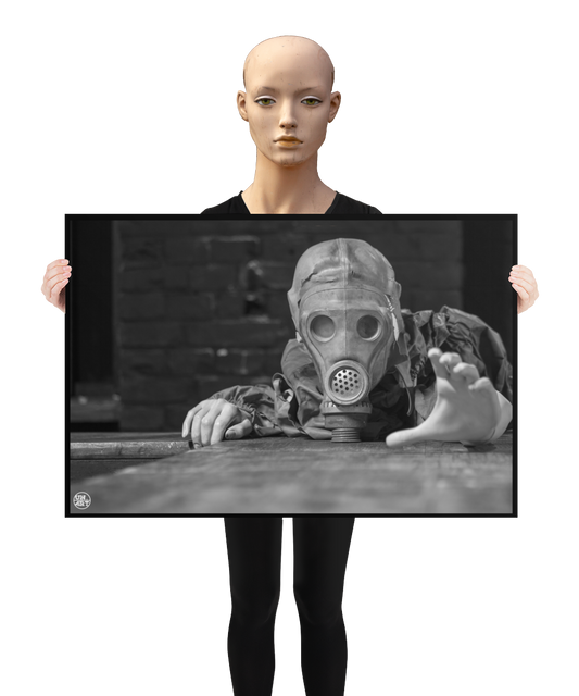 un4rt - a poster. black and white photographie of a mannequin wearing a gas mask. the mannequin stretches out one arm and reaches for help. the mannequin lies on a wooden planket, but the body is not visible. direct front view. black brick wall in the background. a mannequin s holding the poster.