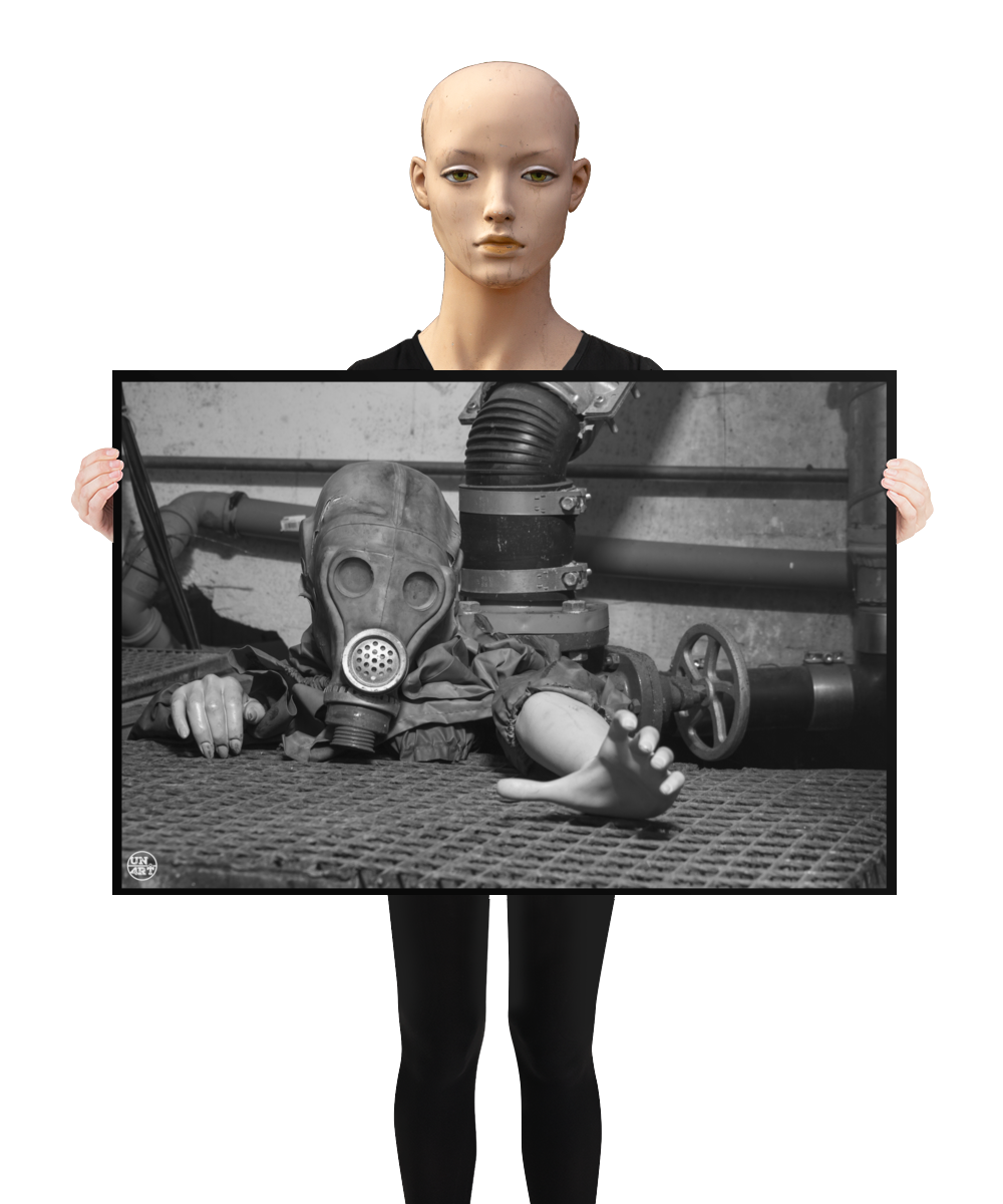 un4rt - a poster. black and white photographie of a mannequin wearing a gas mask. the mannequin stretches out one arm and reaches for help. the mannequin is crawling out of a hole in the ground. grif floor ground. pipes and a shut-off valve next to the mannequin. a mannequin is holding the poster.