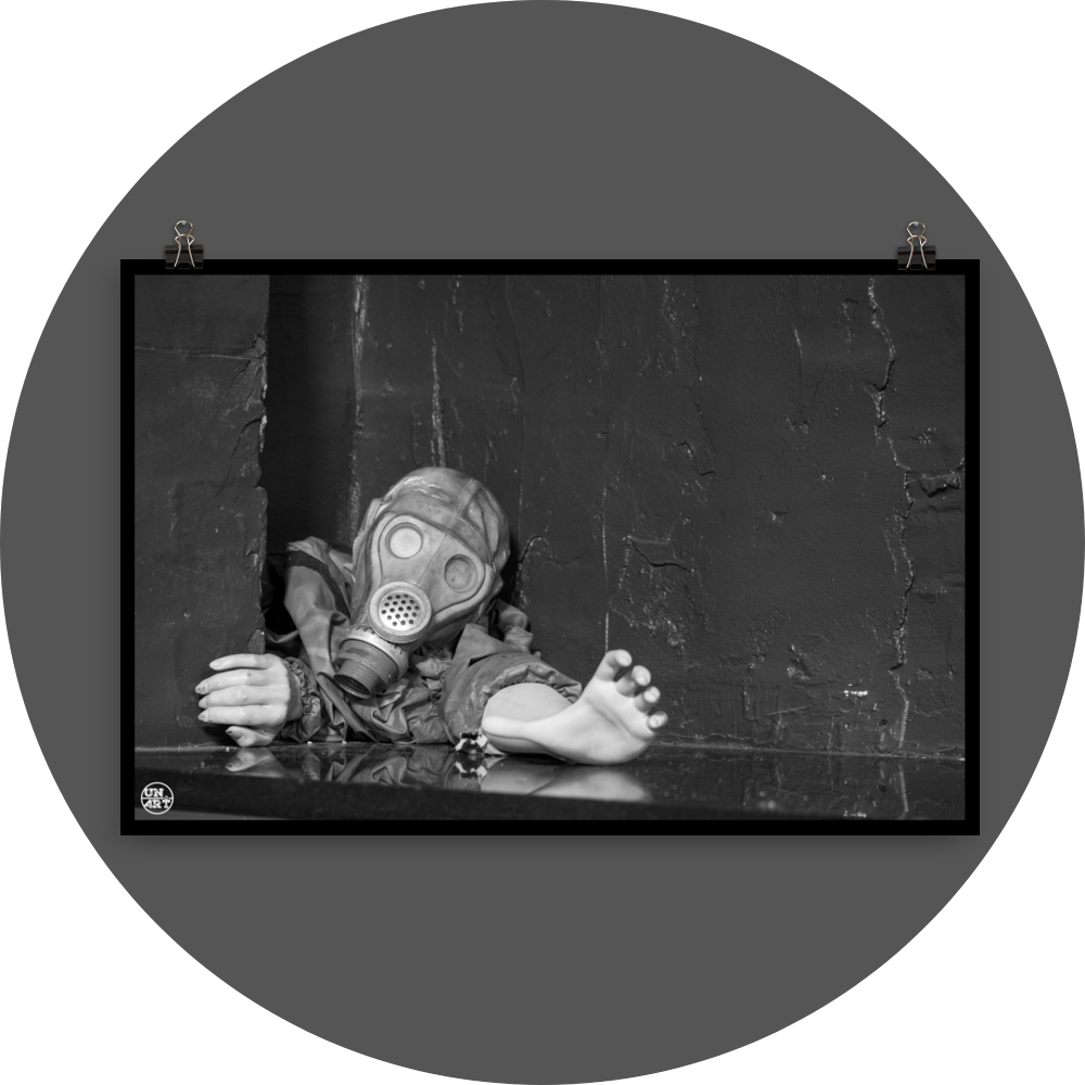 un4rt - black and white photographie of a mannequin wearing a gas mask and forcing its way through a tiny gap between two walls. the mannequing stretches out one arm and reaches for help.