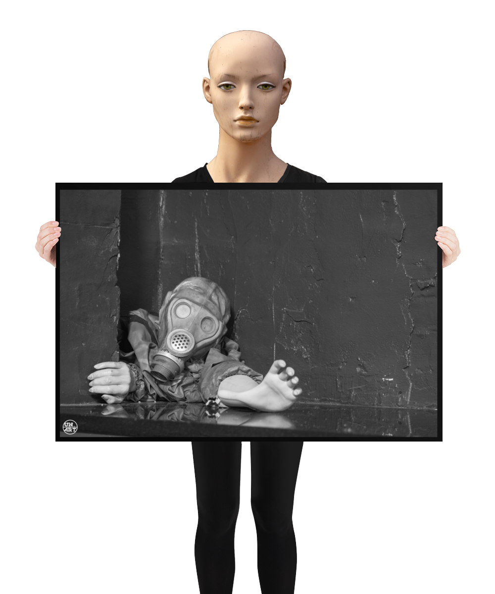 un4rt - a poster. black and white photographie of a mannequin wearing a gas mask and forcing its way through a tiny gap between two walls. the mannequing stretches out one arm and reaches for help. a mannequin is holding the poster.