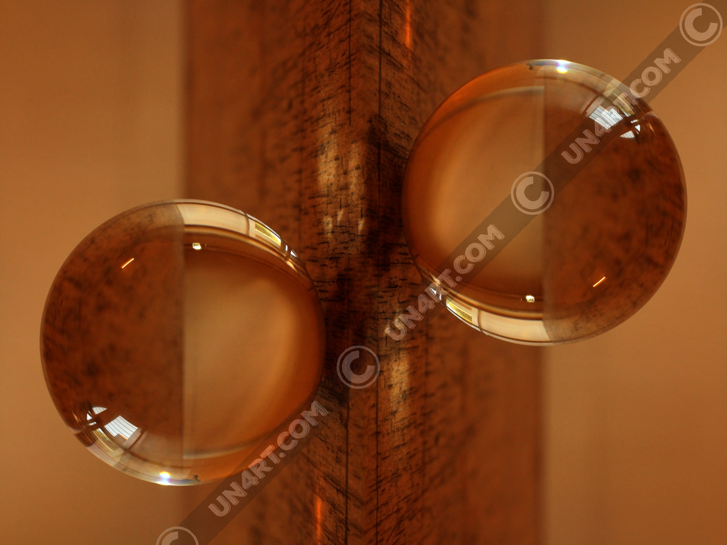 un4rt - the photographie is doubled and then mirrored. both photographies together create the final image. the photographie shows a glass ball on a wooden board. the wooden board is reflecting inside the glasball. the colors range from light brown to orange.