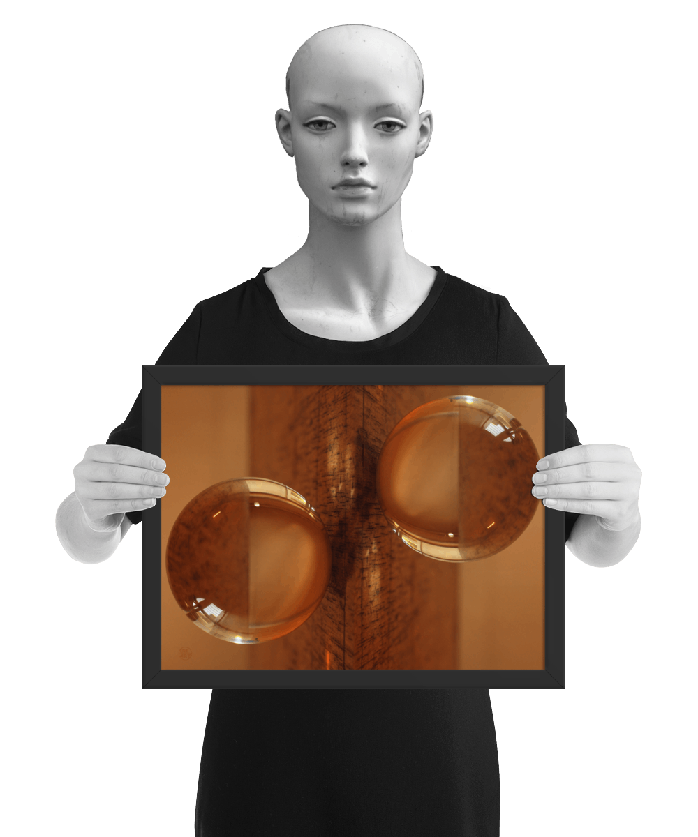 un4rt - the photographie is doubled and then mirrored. both photographies together create the final image. the photographie shows a glass ball on a wooden board. the wooden board is reflecting inside the glasball. the colors range from light brown to orange. the image is framed and presented by a mannequin in black and white.