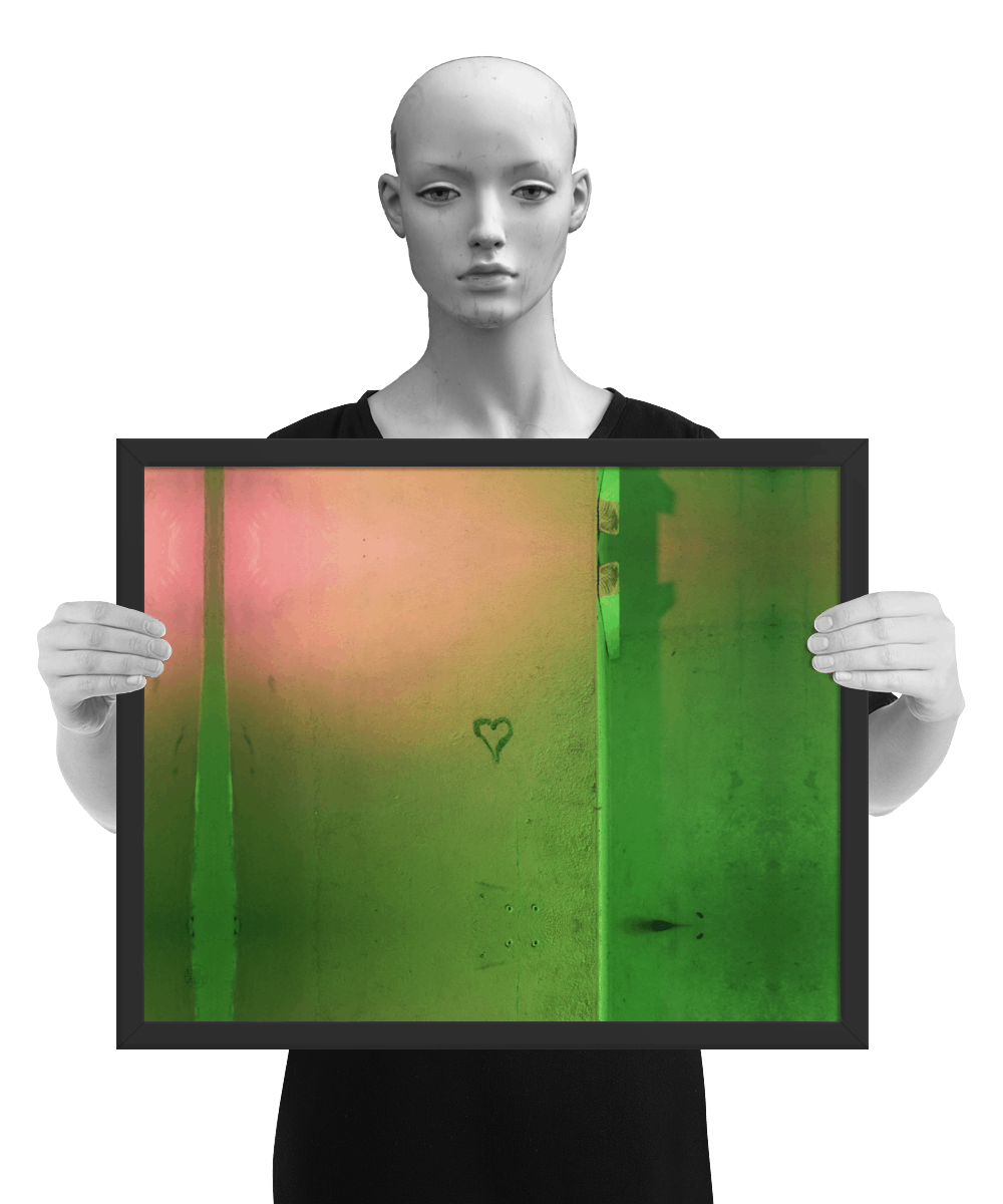 un4rt - the photographie shows a wall that is colored in green, ochre and pink. the symbol of a heart is painted on the wall. the image is framed and presented by a mannequin in black and white.