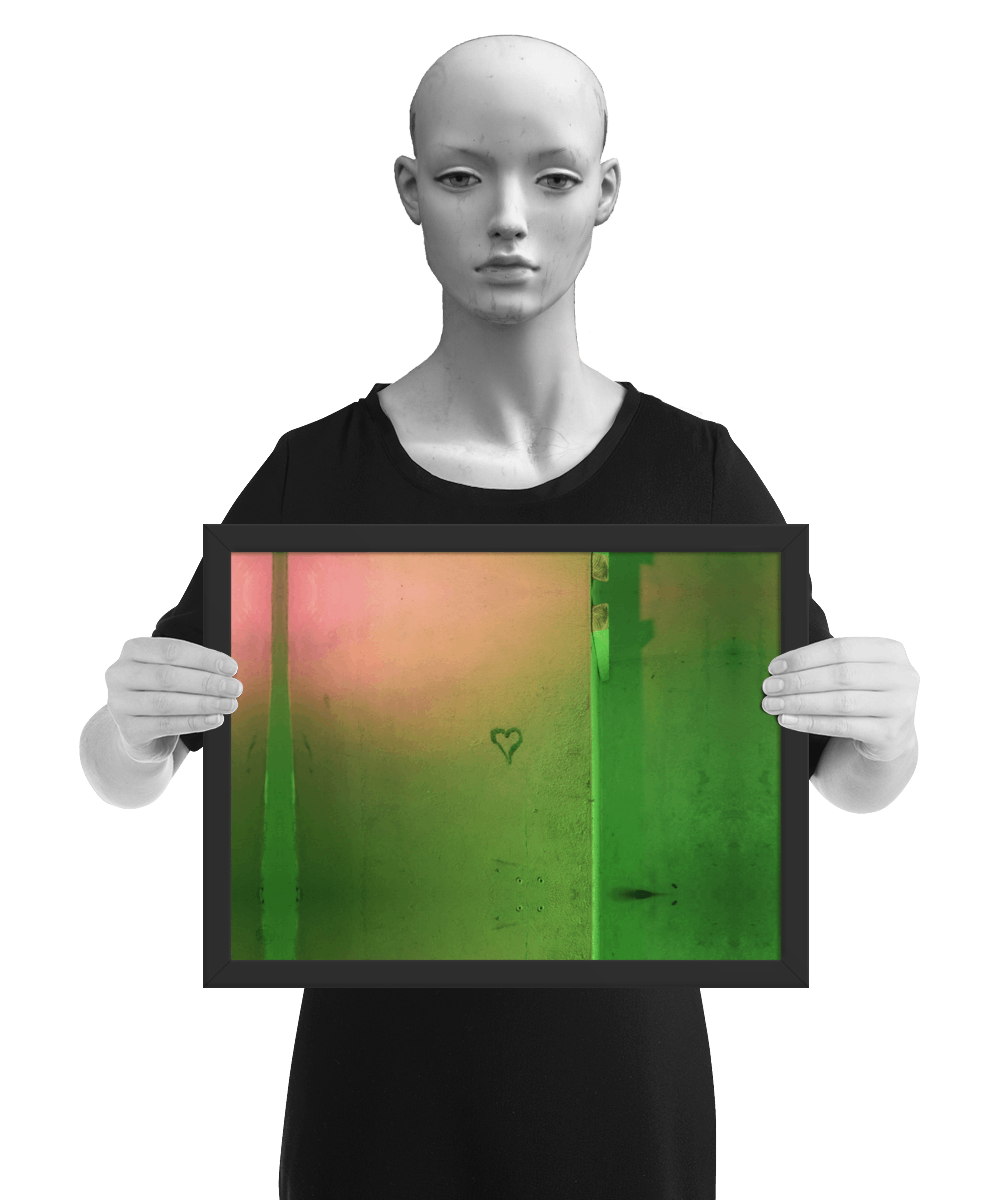 un4rt - the photographie shows a wall that is colored in green, ochre and pink. the symbol of a heart is painted on the wall. the image is framed and presented by a mannequin in black and white.