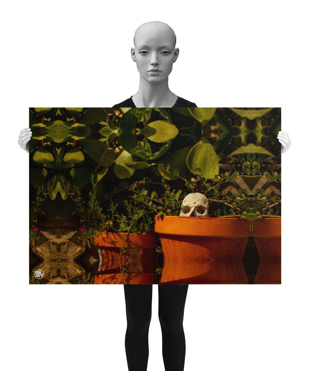 un4rt - a poster. a mirror-framed photographie of a tiny skull looking out of a flower pot. plants with small and big green leaves around the skull. the poster is presented by a model in black and white.
