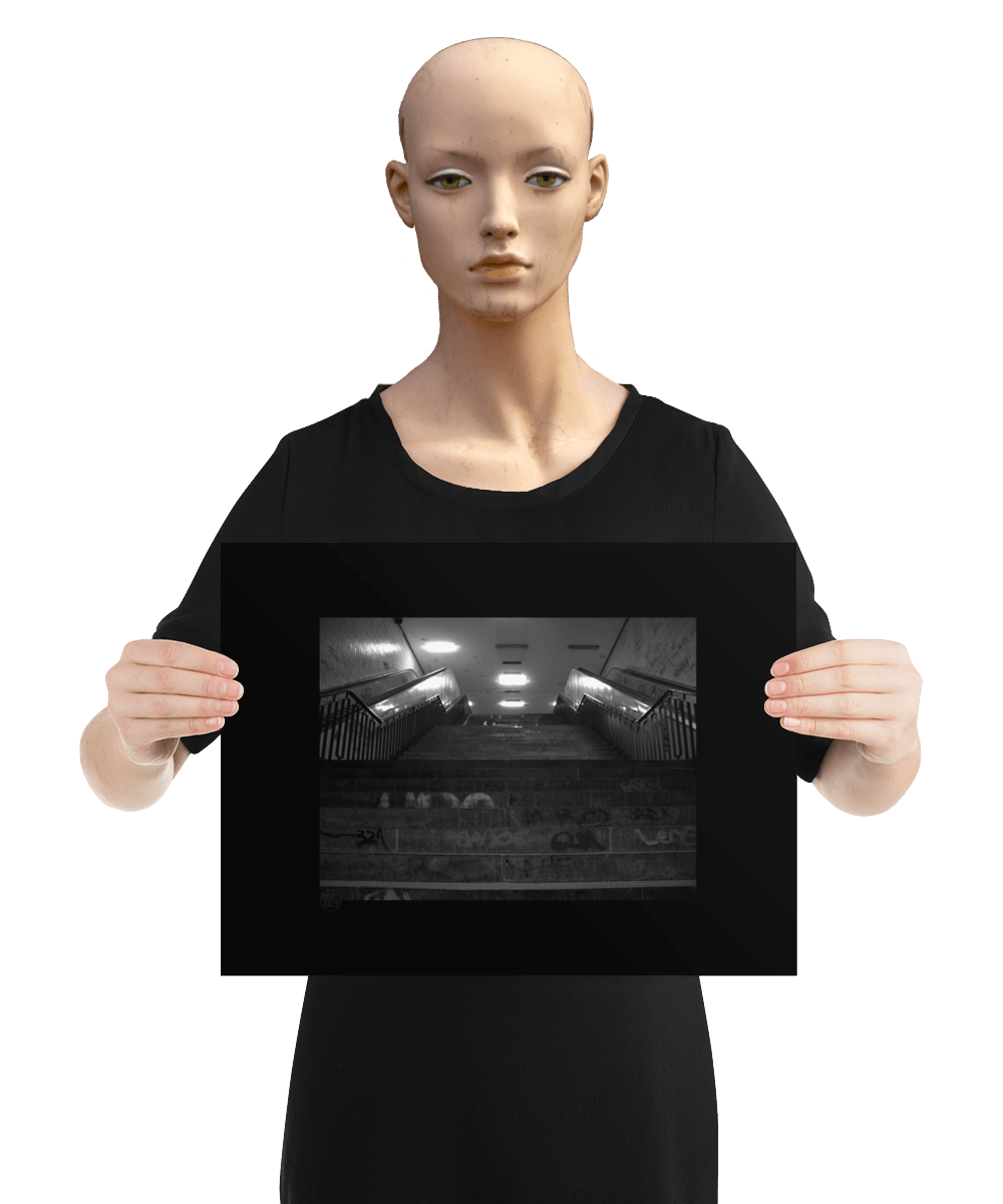 un4rt - a black and white photographie of a former underground trespas that once was part of the train station "alexanderplatz in berlin. stairway. graffities on the stairs and the walls. the image is held by a mannequin.