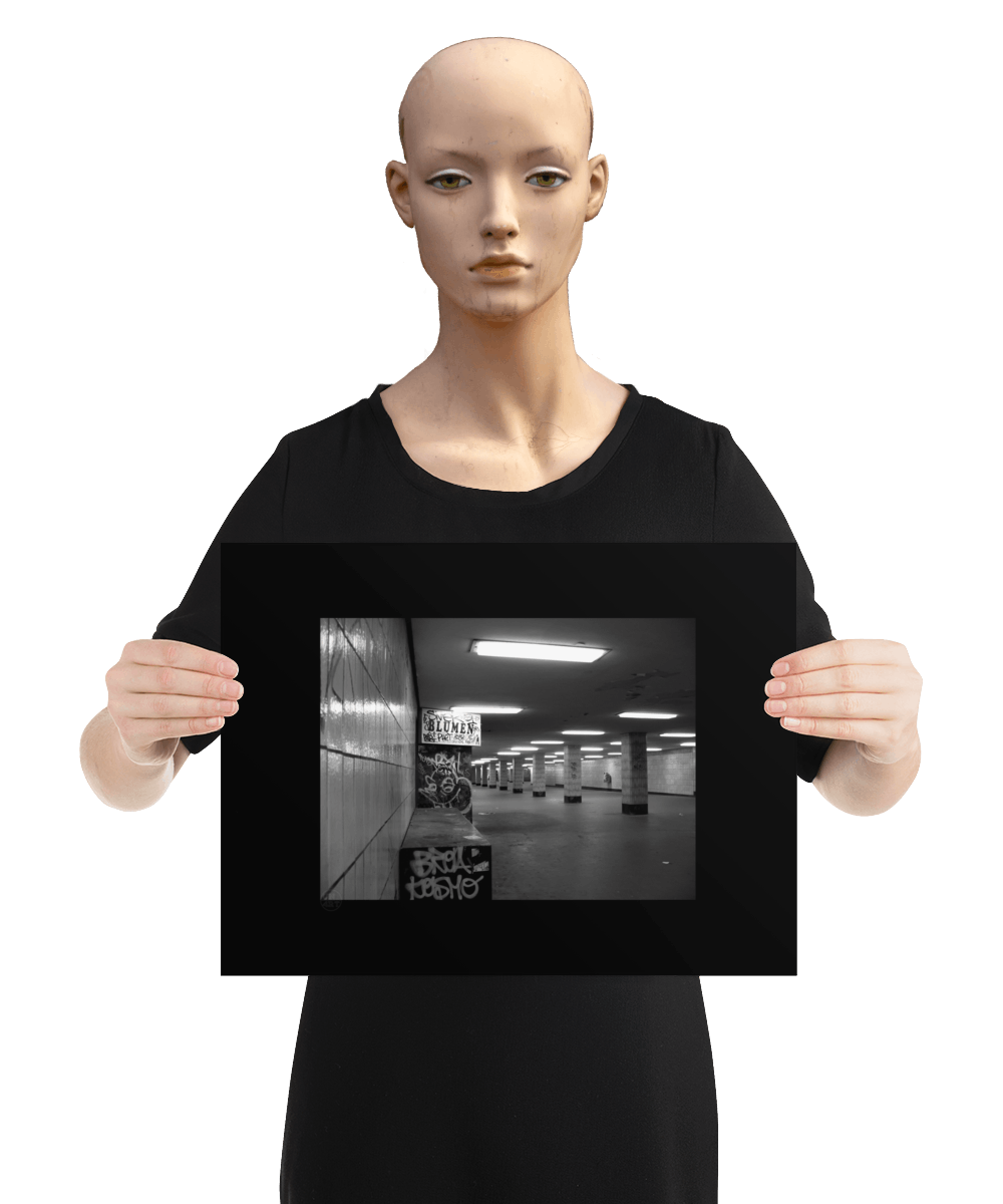 un4rt - a black and white photographie of a former underground trespas that once was part of the train station "alexanderplatz in berlin. tiled square columns support the ceiling. the left wall also has a porch of an old flower shop. the porch is full of graffities and the sign of the shop advertises "blumen". the image is held by a mannequin.