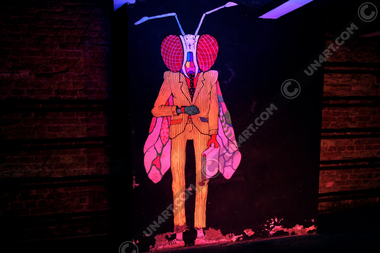 un4rt - the photographie shows a mural of a humanoid insect in a suit with a briefcase on a black wall. the creature is looking at a watch on his wrist. on both side of the black wall there re brick walls with fixed steel pipes. the creature is colorful with a yellow suit, red eyes colored wings and a white head.