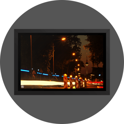 un4rt - the photographie shows a street in berlin. the street is called "puschkinallee" and the view goes along a construction site. at the end of the street berlin´s television tower is clearly visible. time lapse. golden hour. trees and city lights.