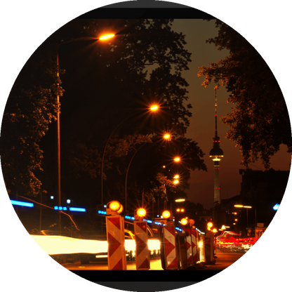un4rt - the photographie shows a street in berlin. the street is called "puschkinallee" and the view goes along a construction site. at the end of the street berlin´s television tower is clearly visible. time lapse. golden hour. trees and city lights.