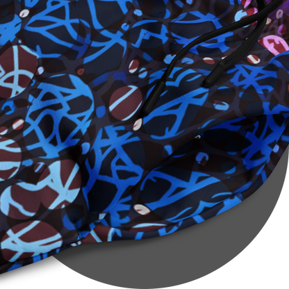 UN4RT chakra dots all-over-print jogger detail – circular close-up of deep blue fabric panel showing anarchic graffiti lettering and circle motifs in electric blue and light blue tones with scattered small white rhinestone dots, black drawstring visible.