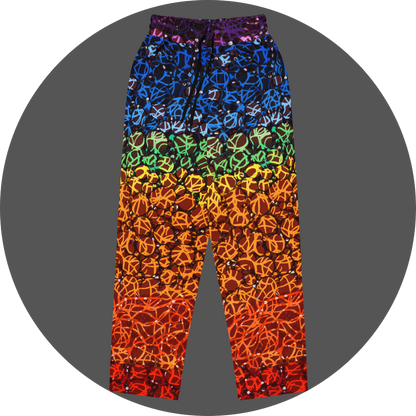 UN4RT chakra dots all-over-print jogger front flat – rainbow gradient sweatpants with anarchic graffiti lettering and circle motifs, vertical colour flow from deep purple and blue at waistband through green, yellow, orange to deep red at hem, scattered white rhinestone dots throughout, elasticated drawstring waistband.