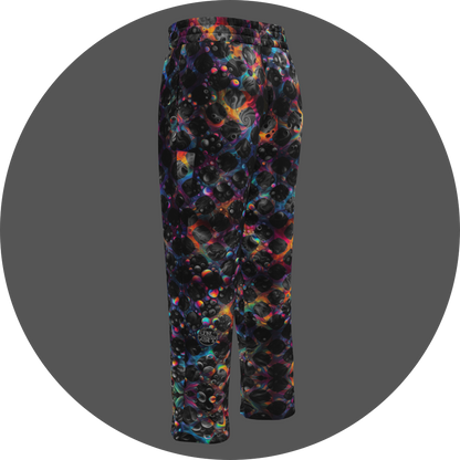 UN4RT cosmic grid all-over-print jogging pants back left view – dark sweatpants with three-dimensional black sphere and bubble cluster pattern, iridescent neon rainbow glow in pink, blue, orange and teal between forms, small UN4RT logo at lower leg, elasticated waistband, straight leg cut.