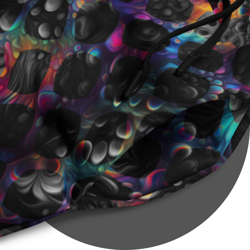 UN4RT cosmic grid all-over-print jogger detail – circular close-up of dark fabric showing dense pattern of three-dimensional black spheres and bubble clusters with iridescent neon rainbow glow in pink, blue, orange and teal between forms, black drawstring visible at waistband.
