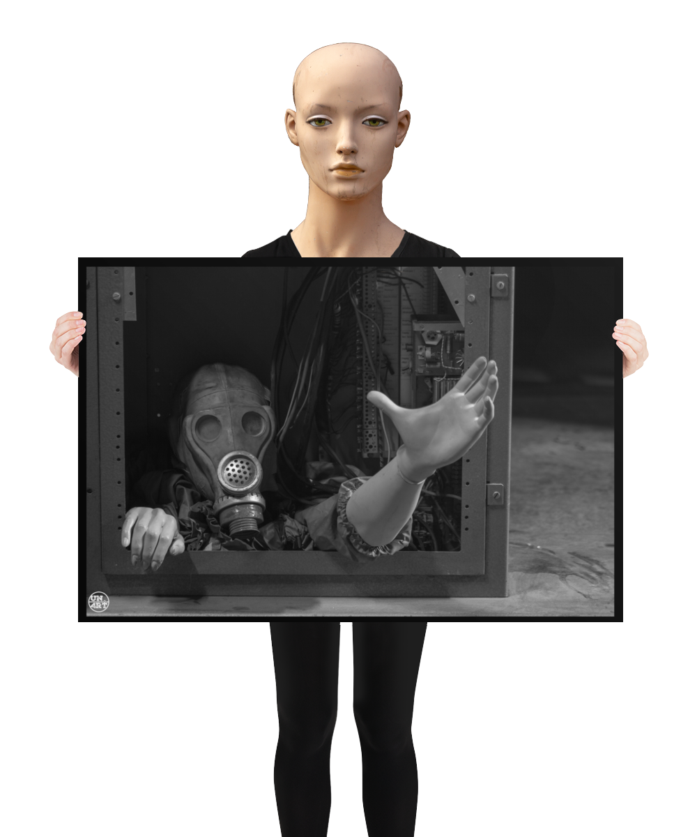 un4rt - a poster. black and white photographie of a mannequin wearing a gas mask. the mannequin stretches out one arm and reaches for help. the body is stuck inside a box with wires and electronic parts. a mannequin is holding the poster.
