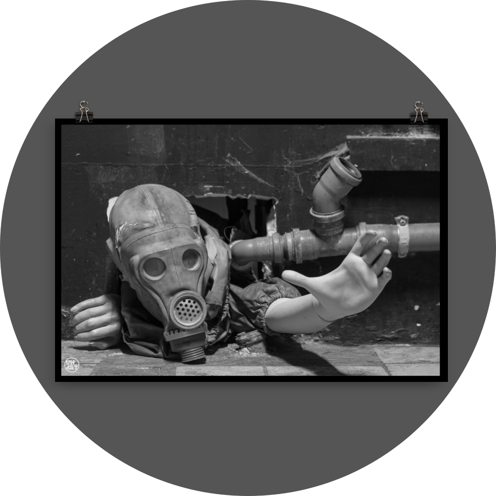 un4rt - black and white photographie of a mannequin wearing a gas mask. the mannequin stretches out one arm and reaches for help. the body is stuck inside a small hole in a wall. unused blackwater pipes next to the mannequin.