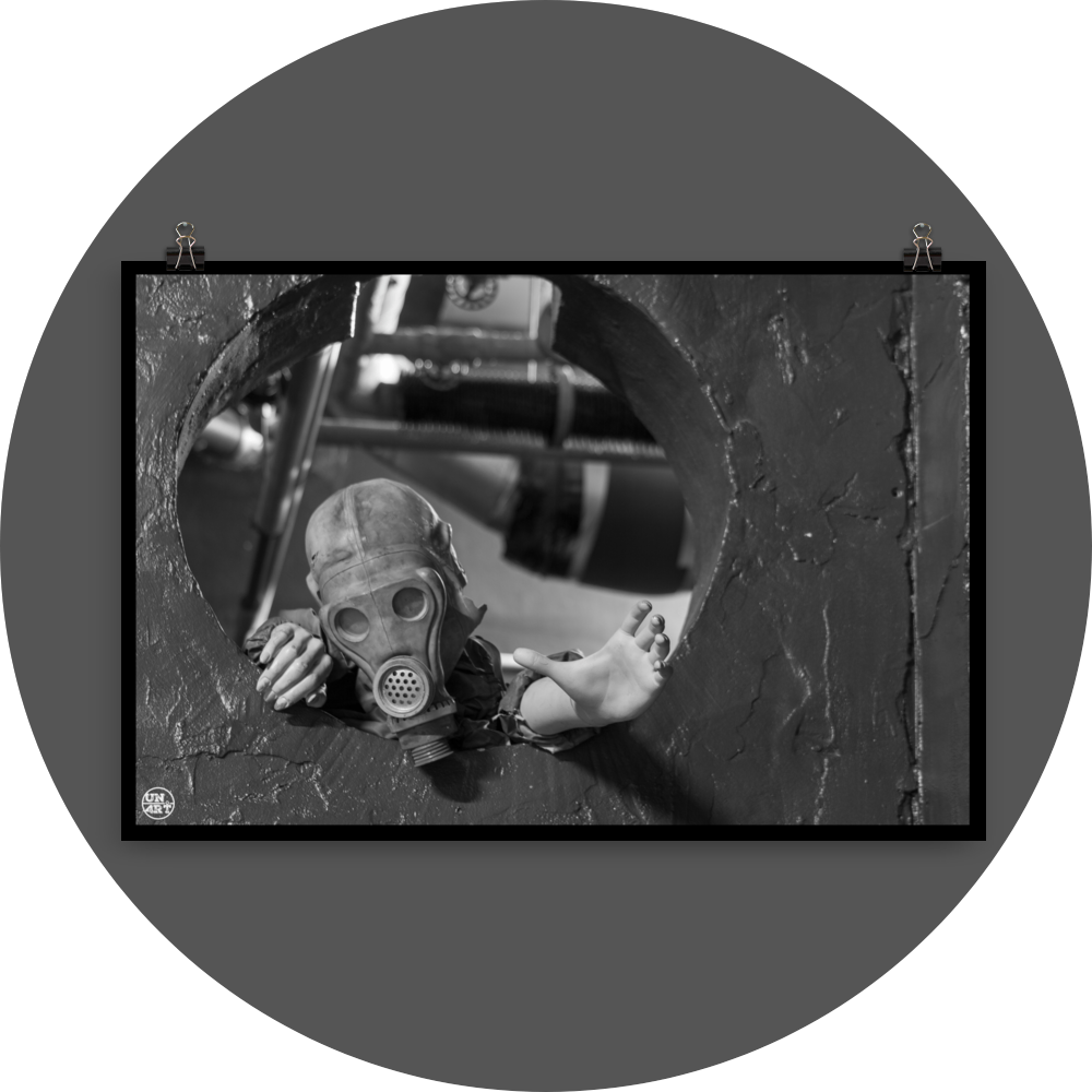 un4rt - black and white photographie of a mannequin wearing a gas mask and climbing through a round hole in a wall. the mannequin stretches out one arm and reaches for help.