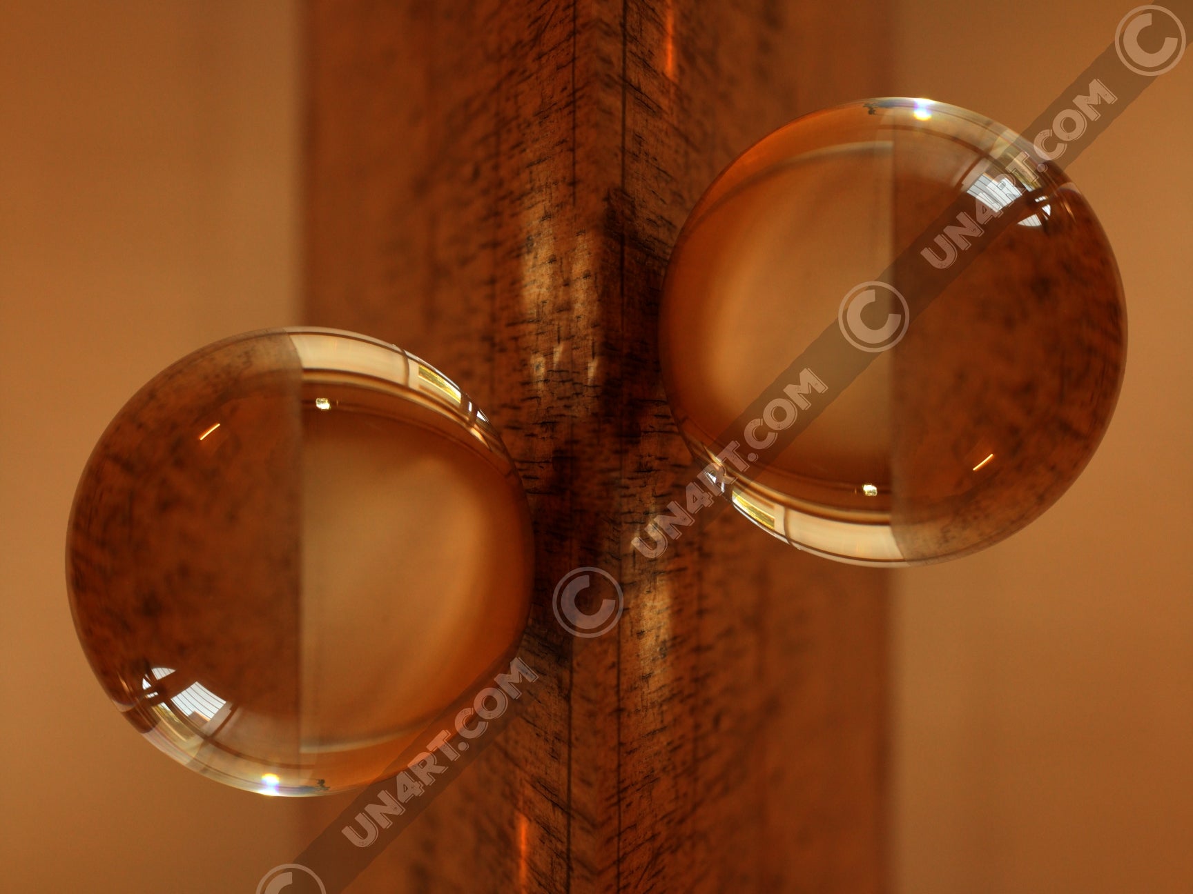 un4rt - the photographie is doubled and then mirrored. both photographies together create the final image. the photographie shows a glass ball on a wooden board. the wooden board is reflecting inside the glasball. the colors range from light brown to orange.
