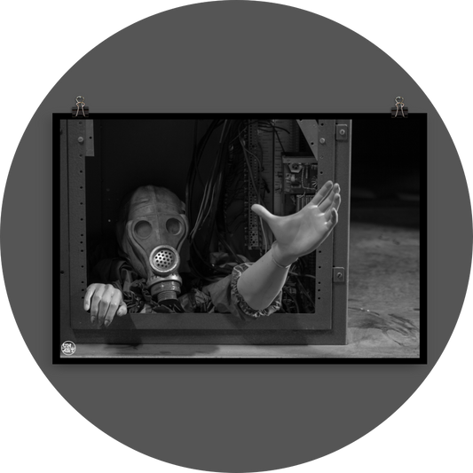 un4rt - black and white photographie of a mannequin wearing a gas mask. the mannequin stretches out one arm and reaches for help. the body is stuck inside a box with wires and electronic parts. 