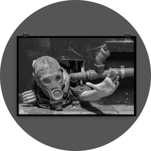 un4rt - black and white photographie of a mannequin wearing a gas mask. the mannequin stretches out one arm and reaches for help. the body is stuck inside a small hole in a wall. unused blackwater pipes next to the mannequin.