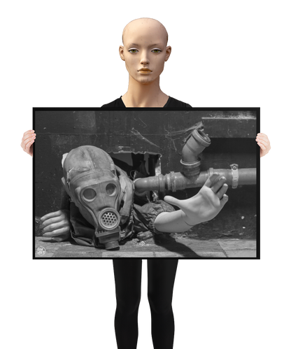 un4rt - a poster. black and white photographie of a mannequin wearing a gas mask. the mannequin stretches out one arm and reaches for help. the body is stuck inside a small hole in a wall. unused blackwater pipes next to the mannequin. a mannequin is holding the poster.