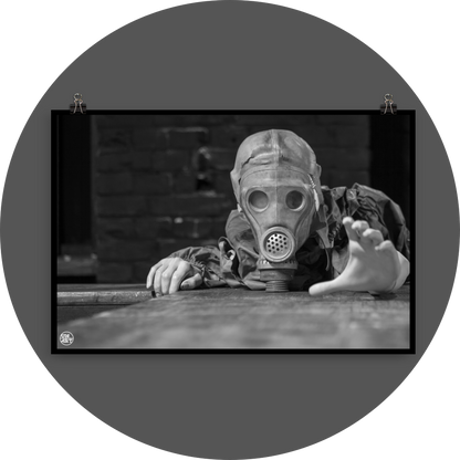 un4rt - black and white photographie of a mannequin wearing a gas mask. the mannequin stretches out one arm and reaches for help. the mannequin lies on a wooden planket, but the body is not visible. direct front view. black brick wall in the background.
