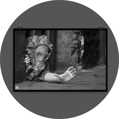 un4rt - black and white photographie of a mannequin wearing a gas mask. the mannequin stretches out one arm and reaches for help. the mannequin is crawling out of a tiny hole in the wall, directly on the floor.