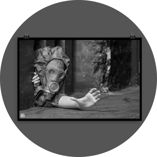 un4rt - black and white photographie of a mannequin wearing a gas mask. the mannequin stretches out one arm and reaches for help. the mannequin is crawling out of a tiny hole in the wall, directly on the floor.