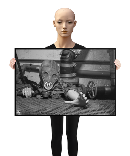 un4rt - a poster. black and white photographie of a mannequin wearing a gas mask. the mannequin stretches out one arm and reaches for help. the mannequin is crawling out of a hole in the ground. grif floor ground. pipes and a shut-off valve next to the mannequin. a mannequin is holding the poster.