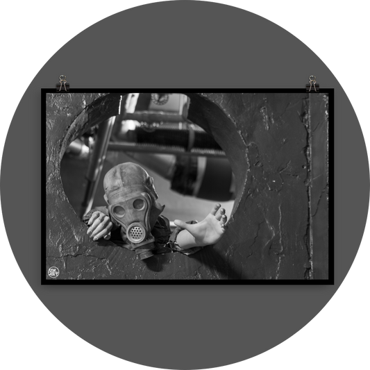 un4rt - black and white photographie of a mannequin wearing a gas mask and climbing through a round hole in a wall. the mannequin stretches out one arm and reaches for help.