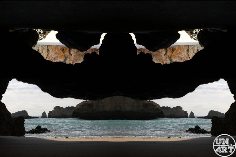 UN4RT imaginarium – symmetrical mirrored sea cave opening framing a teal ocean and rock stacks, dark surreal landscape photography.
