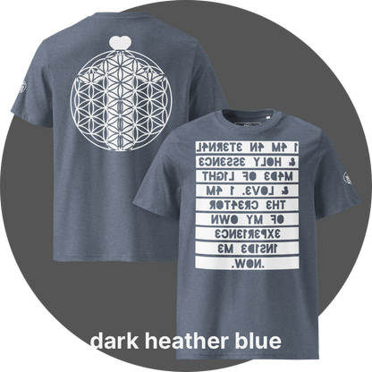 UN4RT dark heather blue organic cotton t-shirt shown from the front and back, front features a large mirrored text artwork on a white rectangular background with reversed dark blue bold lettering reading "i am an eternal & holy essence, made of light & love. i am the creator of my own experience inside me. now.", back features a large white flower of life sacred geometry circle with a white heart shape above it, small circular brand logo visible on both left sleeves.