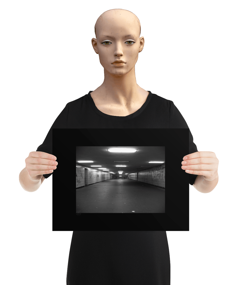 un4rt - a black and white photographie of a former underground trespas that once was part of the train station "alexanderplatz in berlin. graffities on the walls, trash on the ground. the image is held by a mannequin.