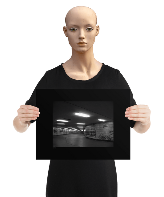 un4rt - a black and white photographie of a former underground trespas that once was part of the train station "alexanderplatz in berlin. advertisings and graffities on the wall. the image is held by a mannequin.