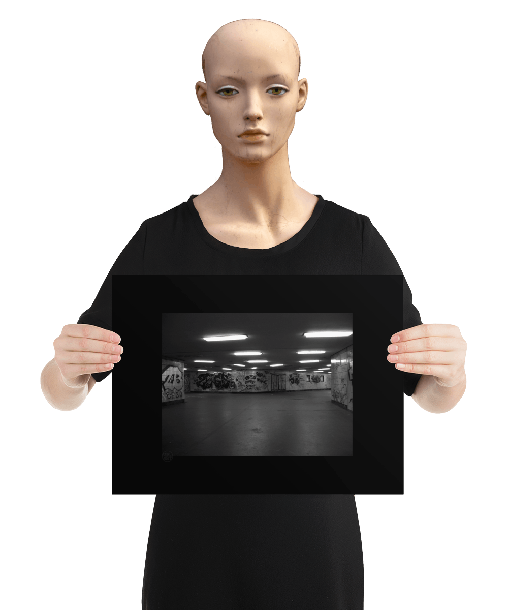 un4rt - a black and white photographie of a former underground trespas that once was part of the train station "alexanderplatz in berlin. big graffities on the wall. the image is held by a manneqin.