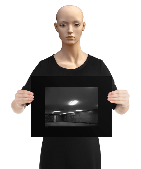 un4rt - a black and white photographie of a former underground trespas that once was part of the train station "alexanderplatz in berlin. the image shows a corner with a closed door. graffities on the wall. one lamp on the ceiling is broken. he image is held by a mannequin.