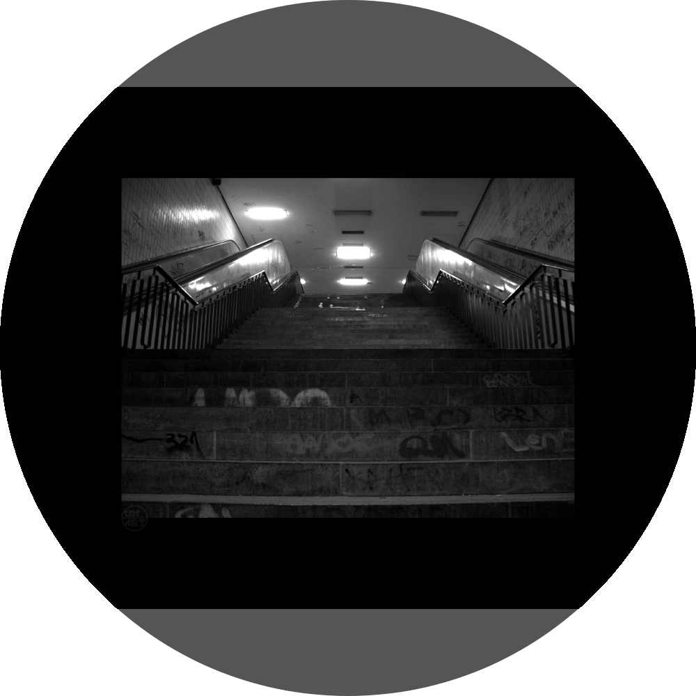 un4rt - a black and white photographie of a former underground trespas that once was part of the train station "alexanderplatz" in berlin. stairway. graffities on the stairs and the walls.