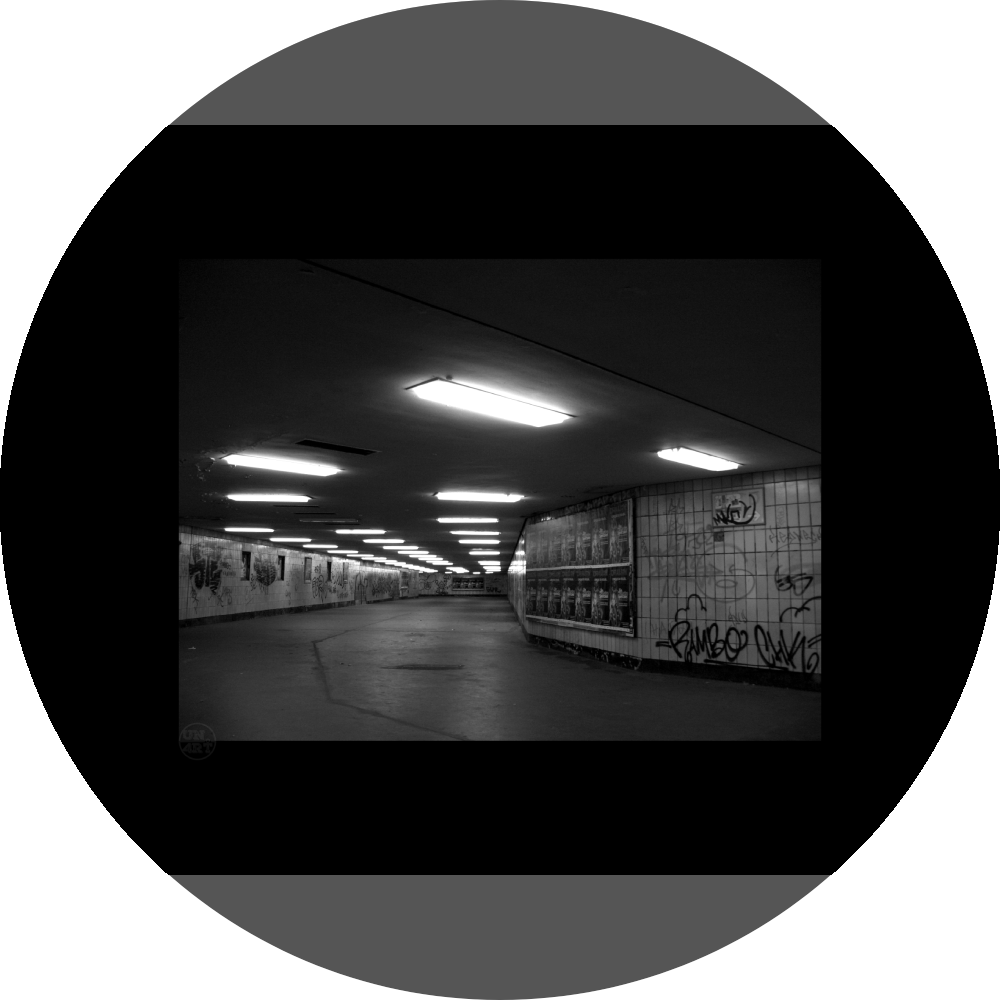un4rt - a black and white photographie of a former underground trespas that once was part of the train station "alexanderplatz" in berlin. advertisings and graffities on the wall.