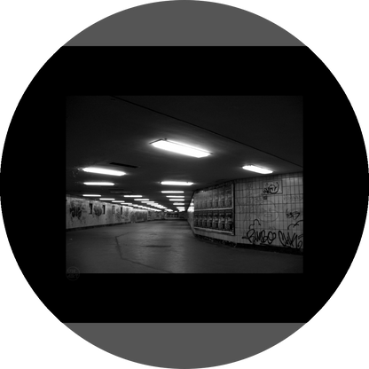 un4rt - a black and white photographie of a former underground trespas that once was part of the train station "alexanderplatz" in berlin. advertisings and graffities on the wall.
