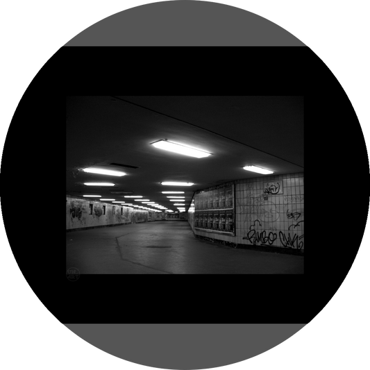 un4rt - a black and white photographie of a former underground trespas that once was part of the train station "alexanderplatz" in berlin. advertisings and graffities on the wall.