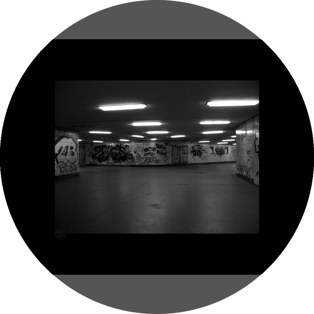 un4rt - a black and white photographie of a former underground trespas that once was part of the train station "alexanderplatz" in berlin. big graffities on the wall. 