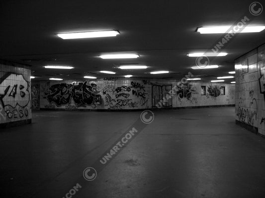 un4rt - a black and white photographie of a former underground trespas that once was part of the train station "alexanderplatz" in berlin. big graffities on the wall. 