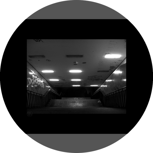 un4rt - a black and white photographie of a former underground trespas that once was part of the train station "alexanderplatz" in berlin. a stairway that is leading down. graffities on the ceiling and the wall. 